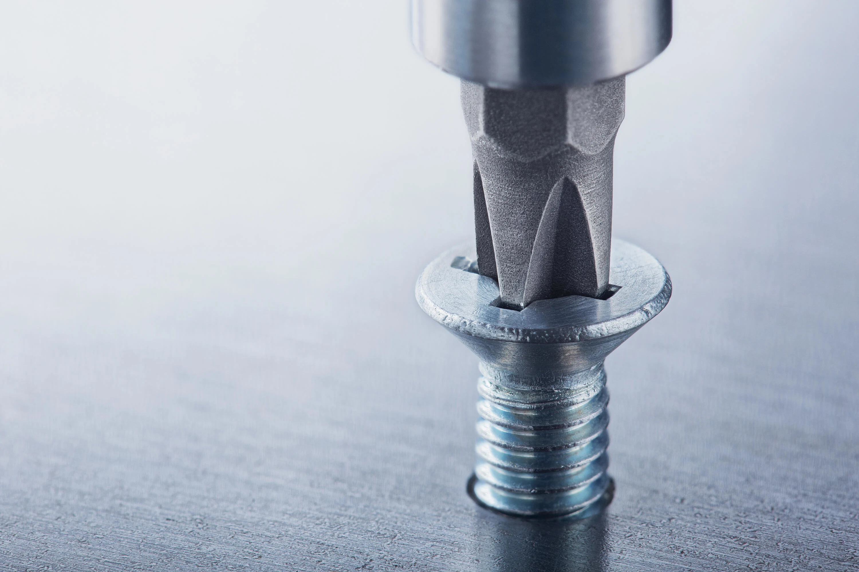 
一颗带十字槽驱动的螺钉被拧入金属板。