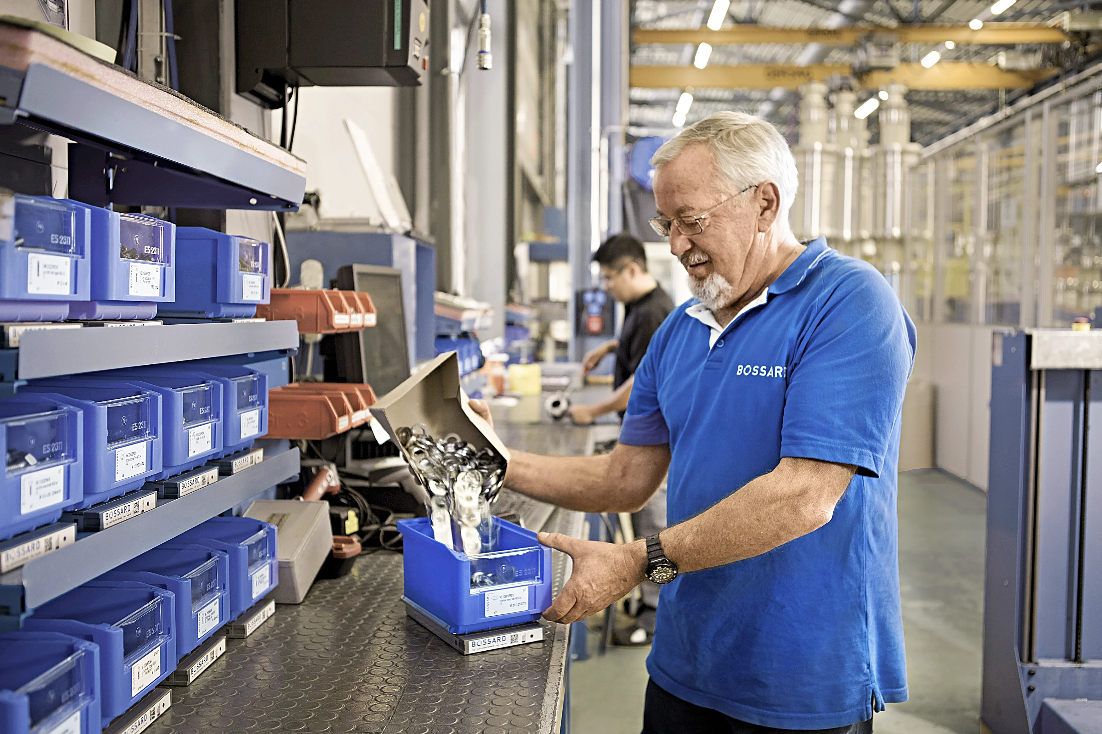 身穿蓝色衬衫的Bossard员工在库存位置补充SmartBin容器。