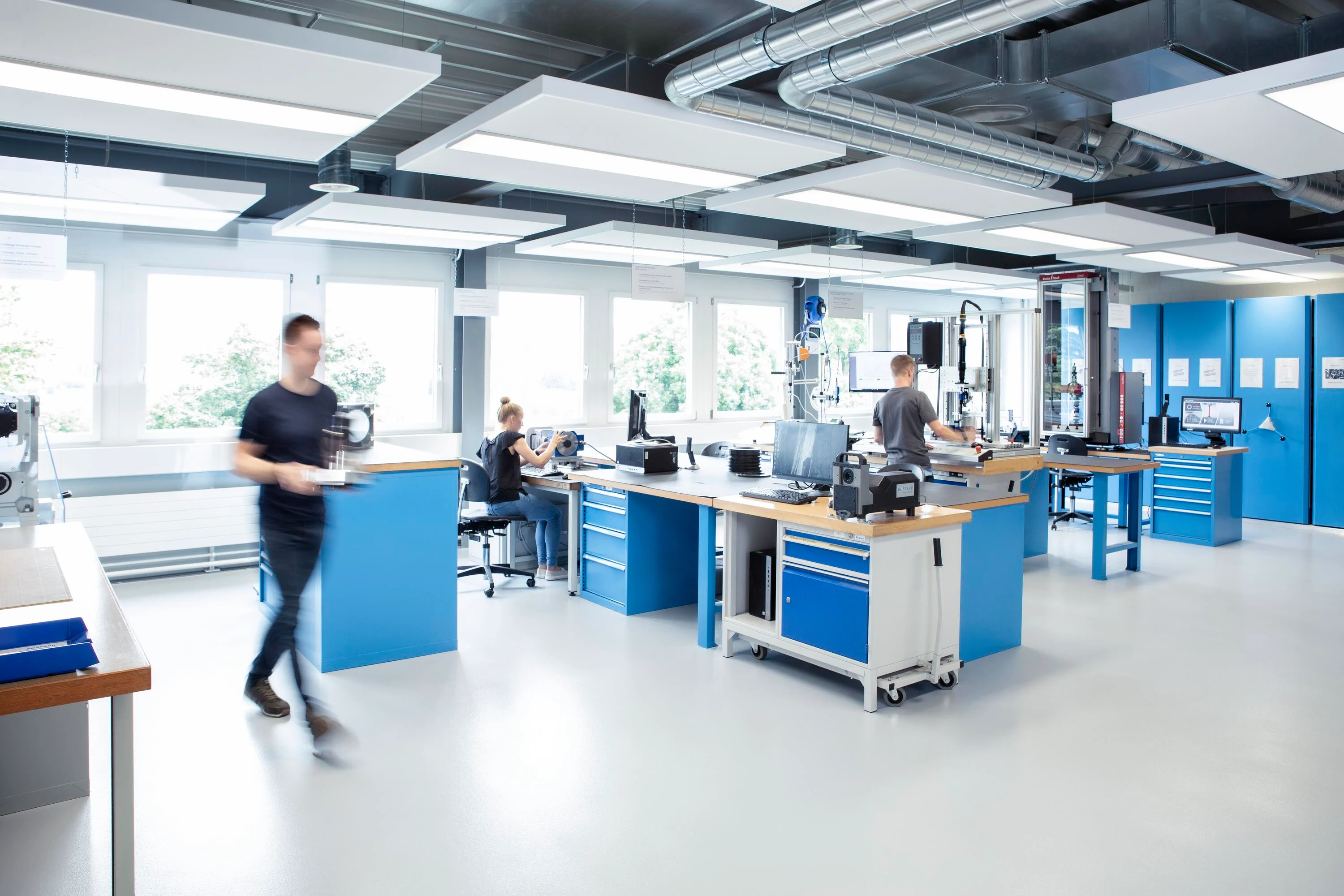 三位工程师在设备齐全的实验室中合作进行各种测试,清晰可见团队和测试设备。