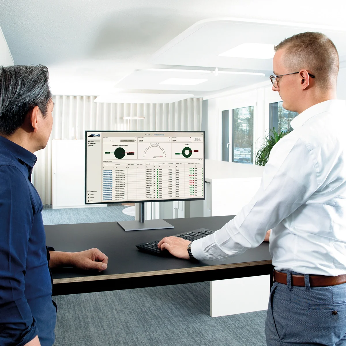 两名男子在桌前，专注于显示数据报告的电脑屏幕。