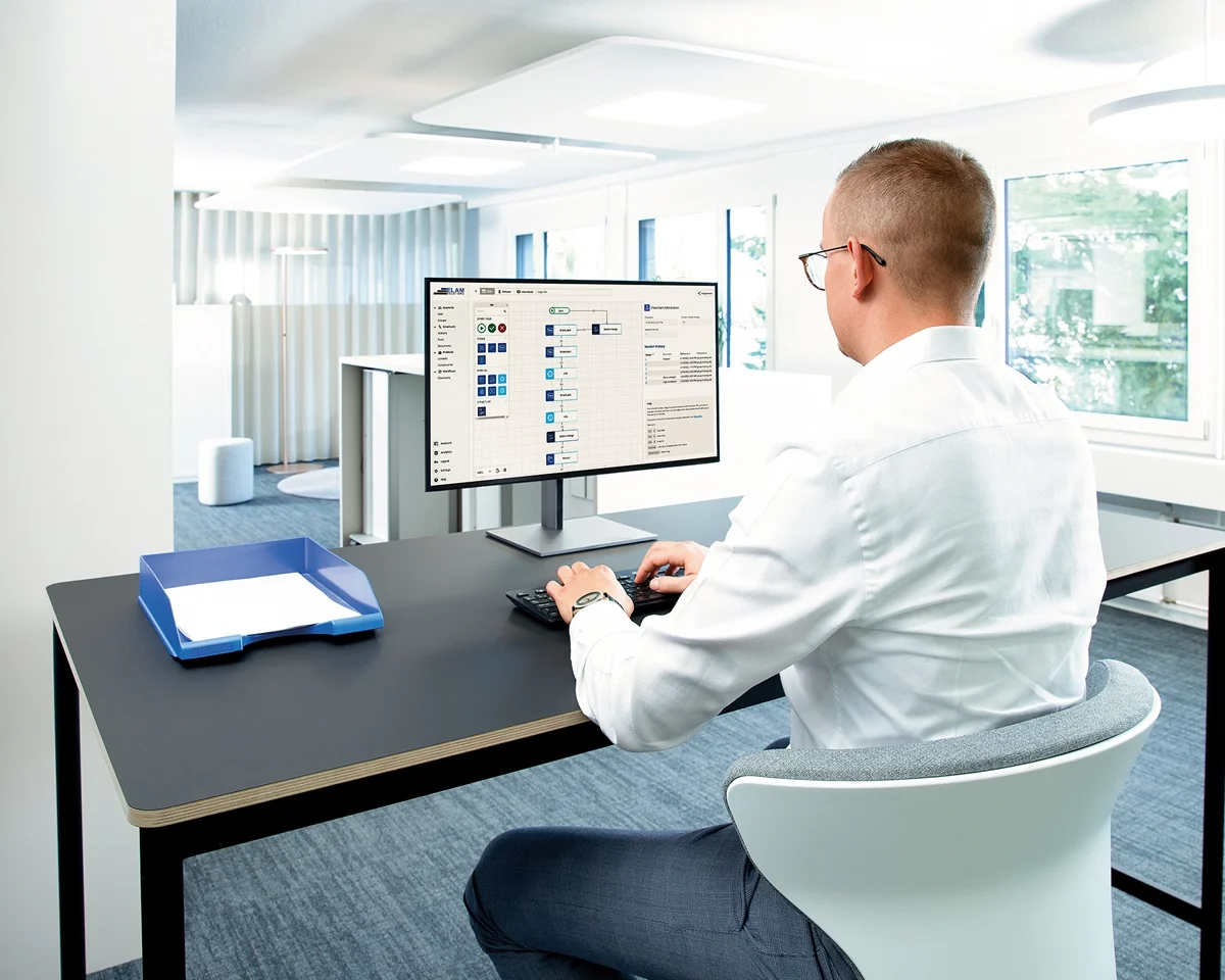 一个男人坐在桌子旁,专注于电脑屏幕,投入工作。