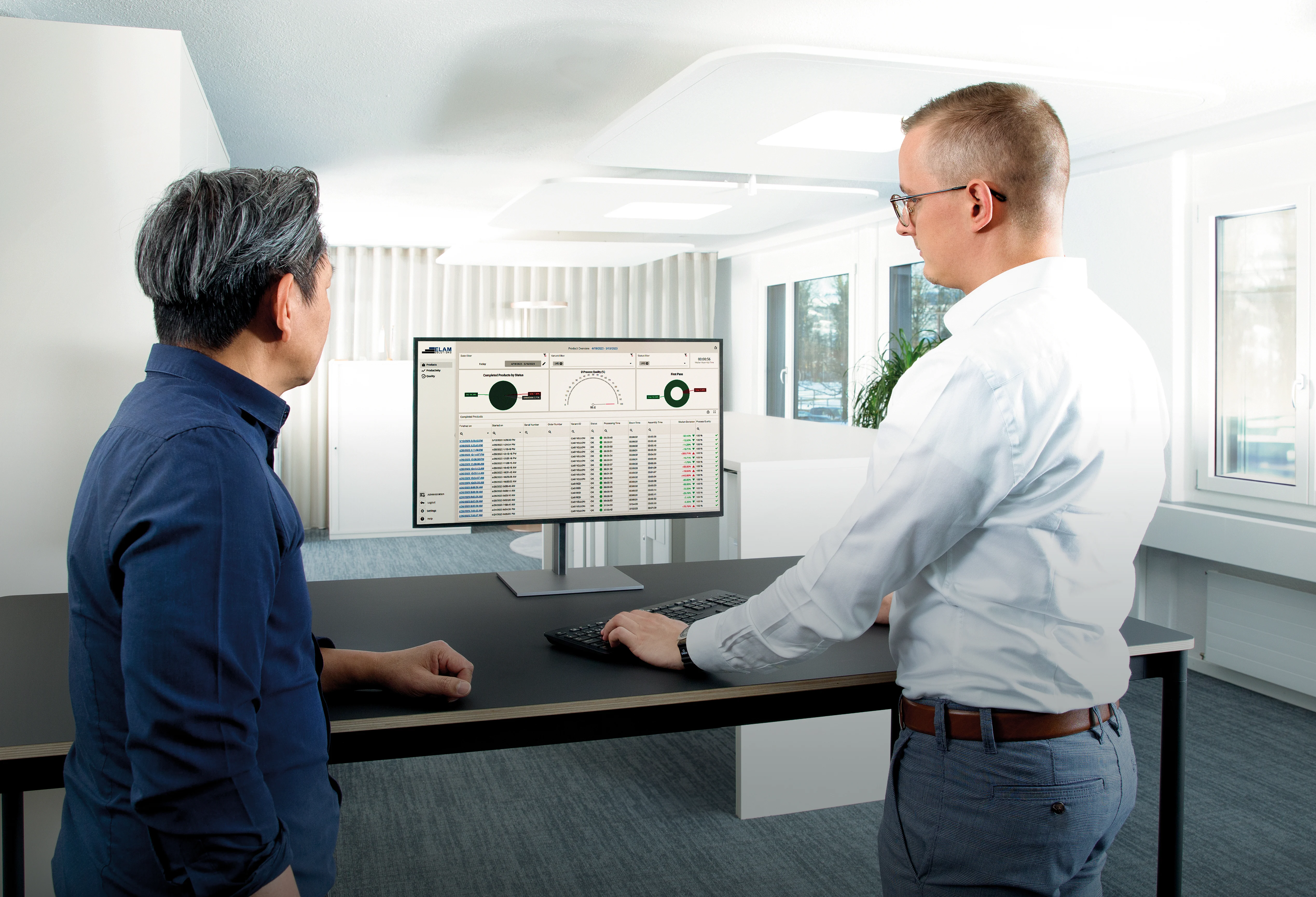 两名男子在桌前，专注于显示数据报告的电脑屏幕。